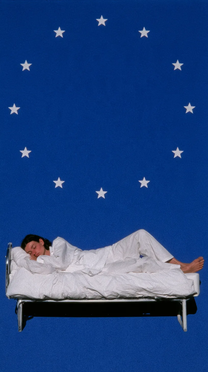 Una mujer en pijama blanco duerme de lado sobre una cama metálica que flota en un fondo azul, bajo un círculo de estrellas blancas.