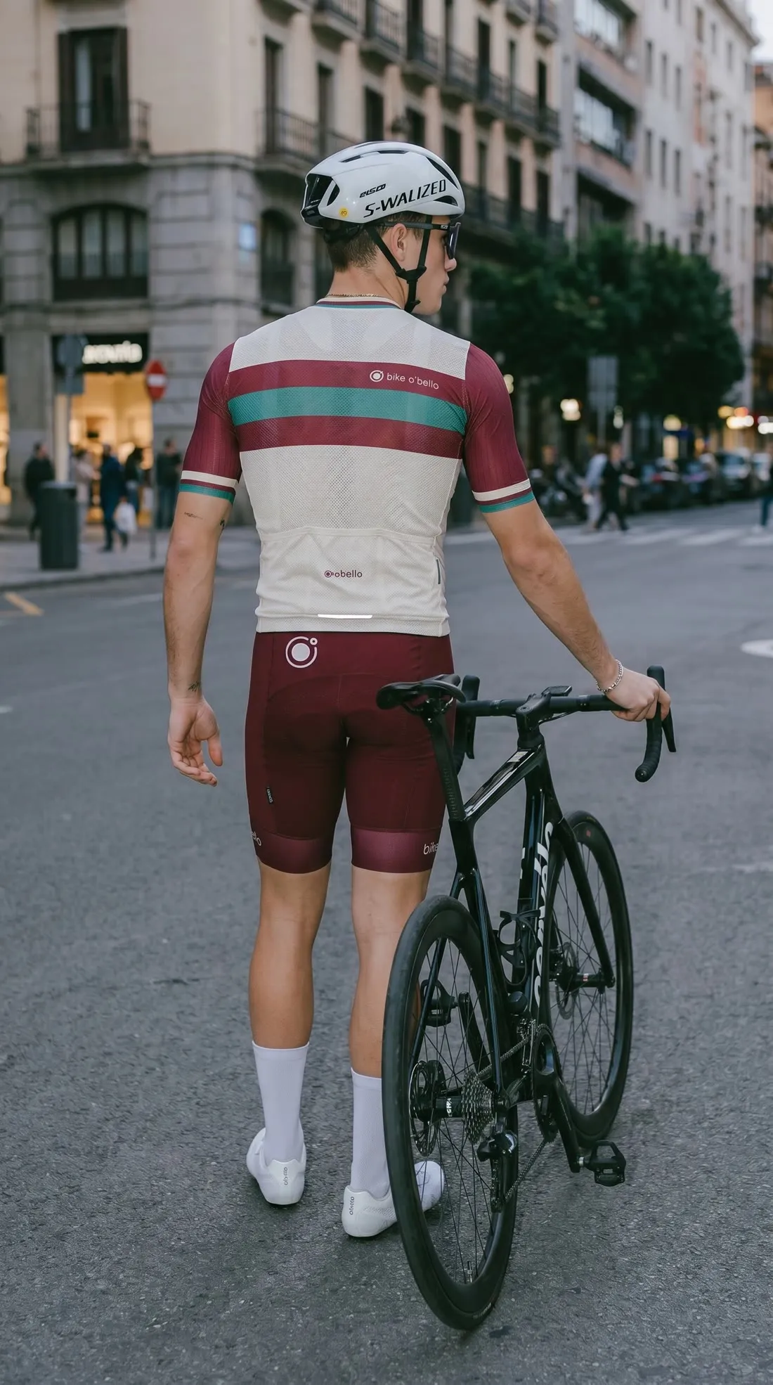 De espaldas, andando con la bici por una calle céntrica.